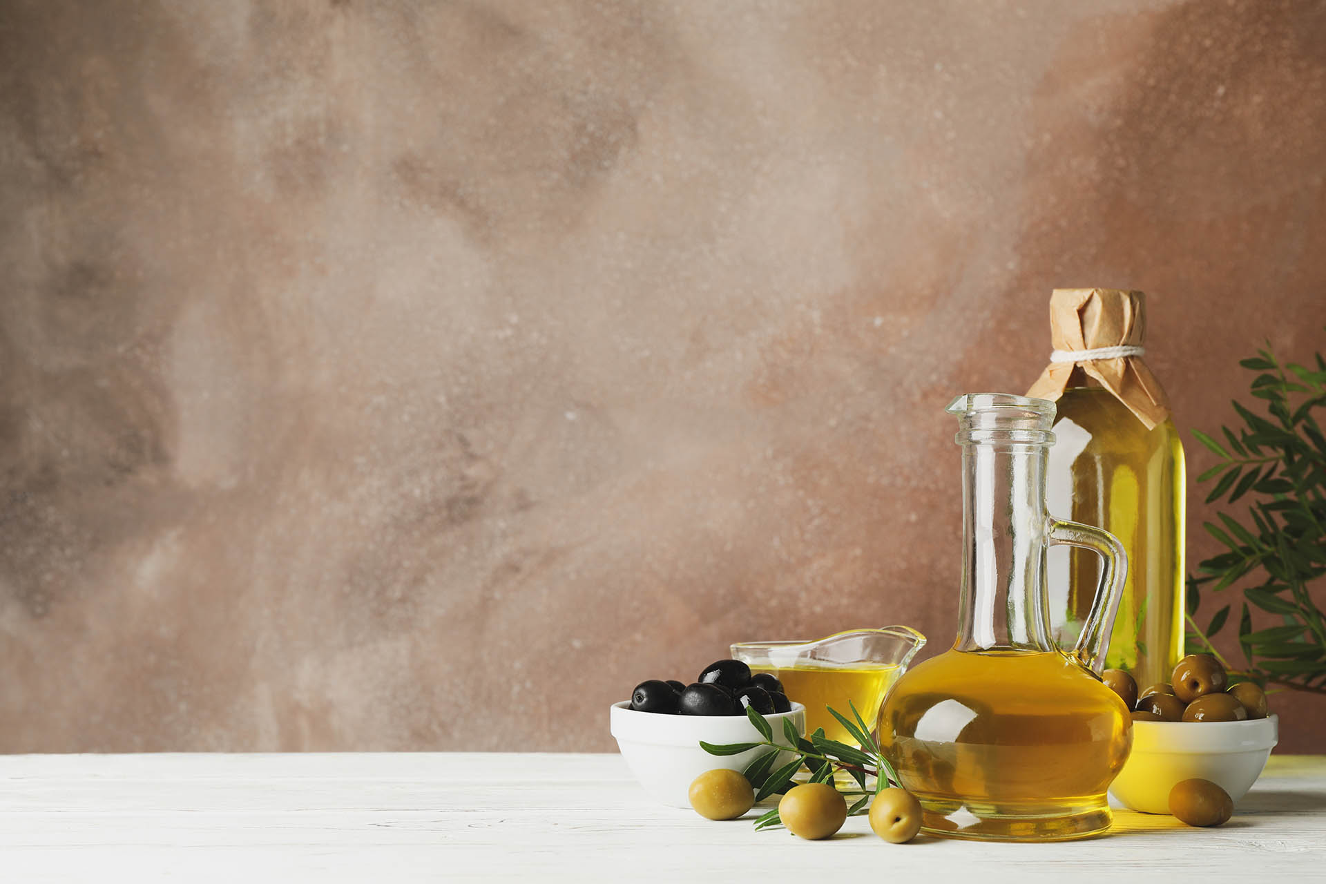 Composition with olive oil and olives against brown background, space for text